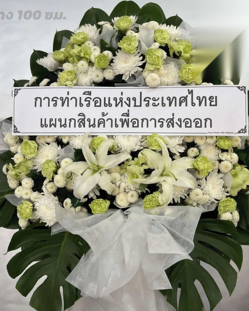 พวงหรีดดอกไม้สดโทนขาวป้ายลงชื่อในนามหน่วยงาน ตั้งอยู่ที่ศาลาวัดในกรุงเทพฯ