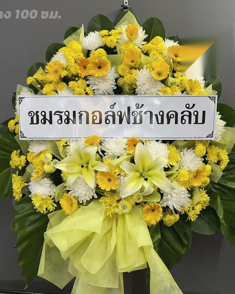 พวงหรีดดอกไม้สดโทนเหลืองพร้อมป้ายชื่อคณะผู้ส่ง ตั้งเรียงที่หน้าศาลาของวัด