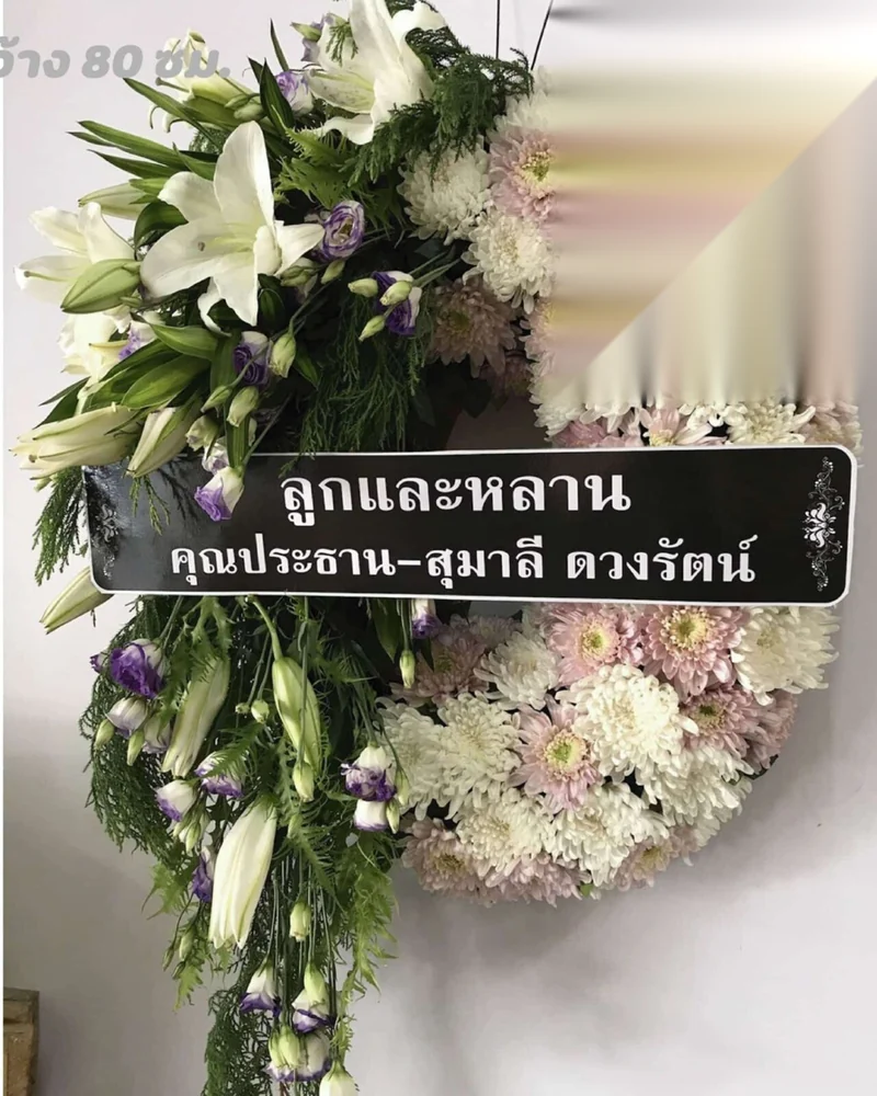พวงหรีดดอกไม้สดโทนขาวม่วง พร้อมป้ายระบุผู้ส่งเป็นลูกและหลาน