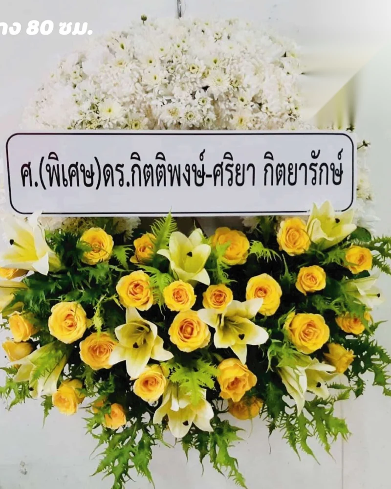 พวงหรีดดอกไม้สดโทนเหลืองขาวพร้อมป้ายชื่อผู้ส่งตัวอักษรอ่านชัด